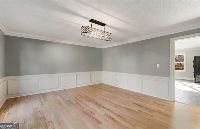 empty room featuring crown molding, a textured ceiling, and wood finished floors