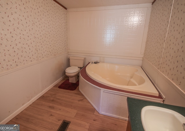 bathroom with wood-type flooring, vanity, a washtub, and toilet