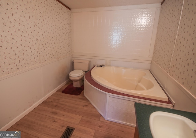 full bath featuring a bath, wood finished floors, a sink, wainscoting, and wallpapered walls
