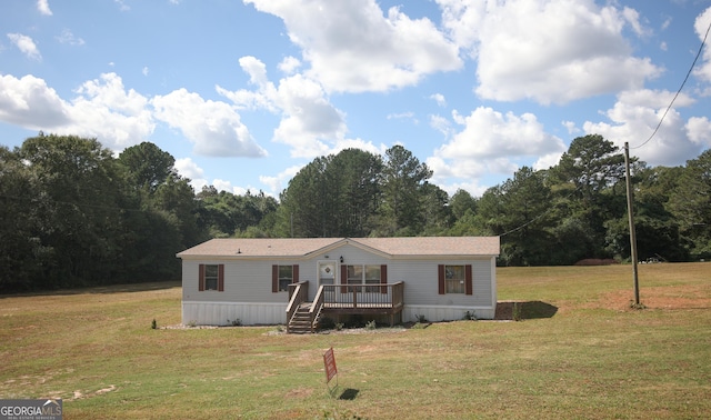 manufactured / mobile home featuring a front yard, a view of trees, and a deck