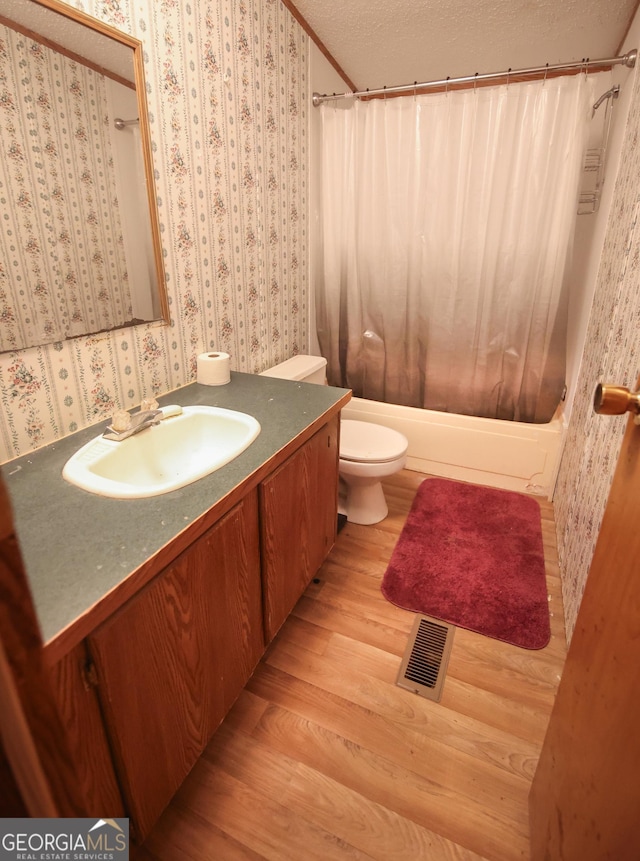 full bathroom with visible vents, toilet, vanity, wood finished floors, and wallpapered walls