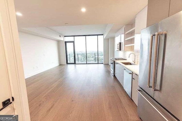 kitchen featuring light hardwood / wood-style flooring, floor to ceiling windows, high end refrigerator, stove, and sink