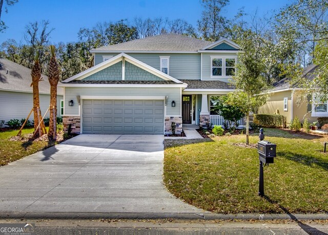 craftsman-style home featuring covered porch, a front yard, and a garage