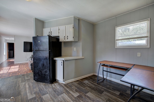 kitchen with white cabinets, black refrigerator, and dark hardwood / wood-style floors