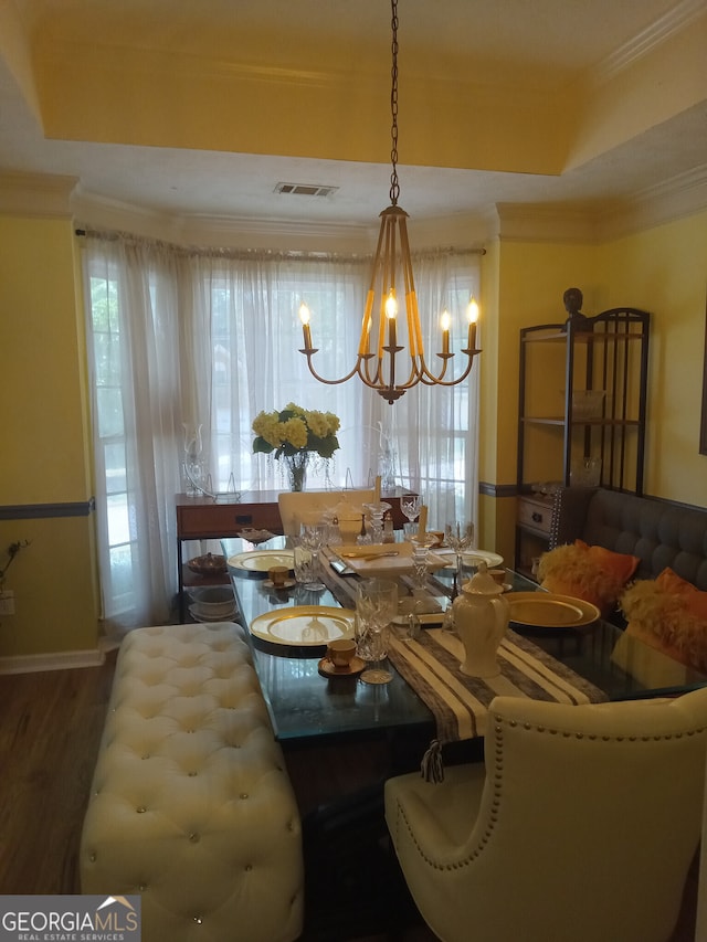 dining space featuring visible vents, dark wood-style flooring, a tray ceiling, crown molding, and a notable chandelier