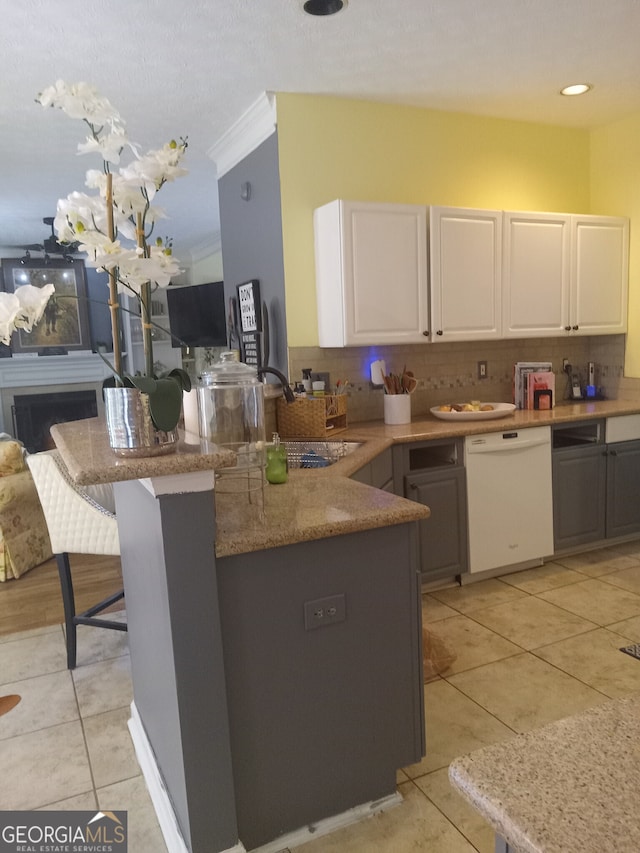 kitchen with white cabinets, dishwasher, a peninsula, and a kitchen bar