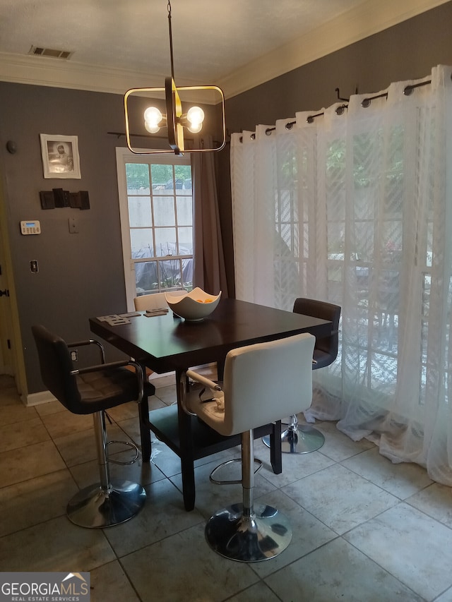 dining space featuring an inviting chandelier, tile patterned floors, visible vents, and crown molding