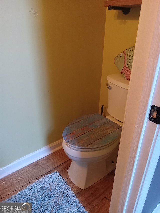 bathroom with toilet, baseboards, and wood finished floors