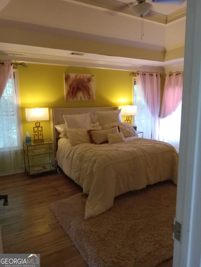 bedroom featuring ornamental molding, visible vents, and wood finished floors