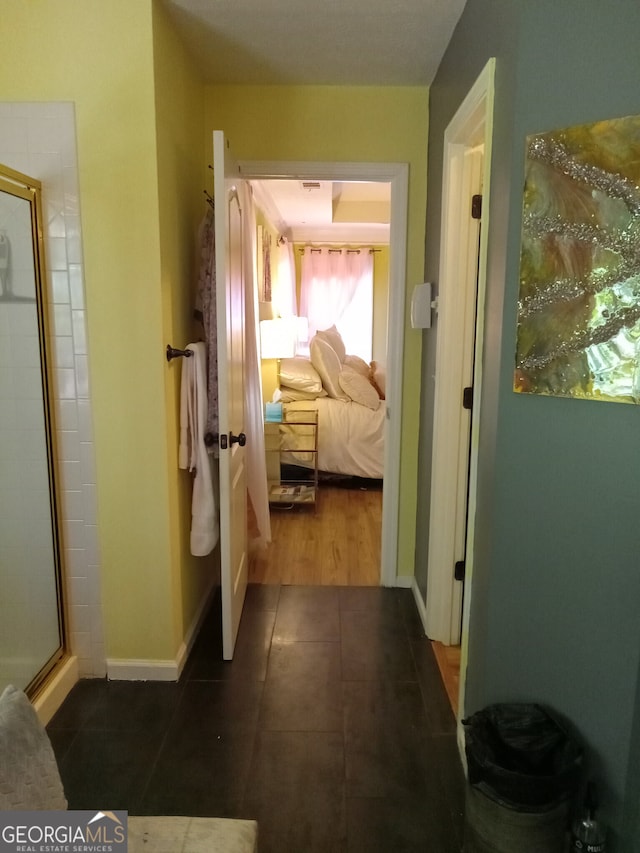 hall featuring dark tile patterned floors and baseboards