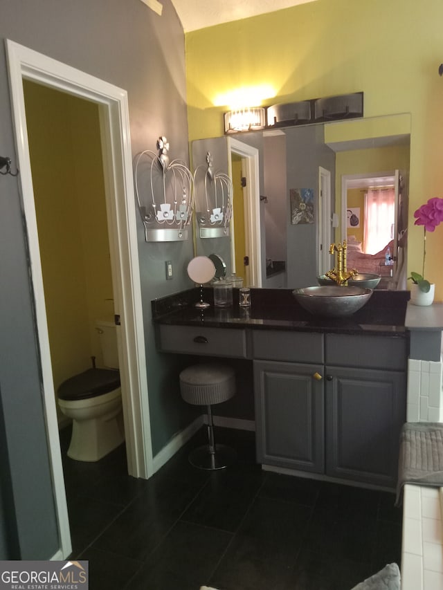 bathroom with toilet, tile patterned floors, baseboards, and vanity