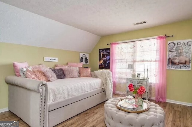 bedroom featuring lofted ceiling, visible vents, baseboards, and wood finished floors