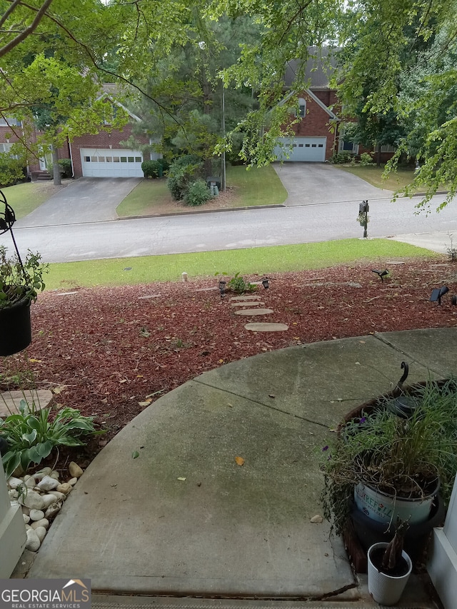 view of yard featuring a garage and concrete driveway