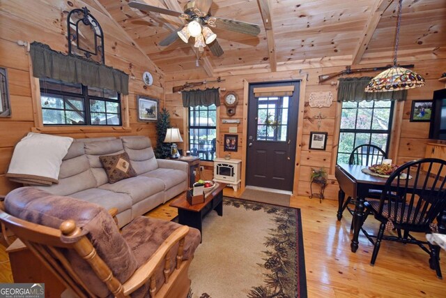 living room featuring lofted ceiling, wood ceiling, light wood-type flooring, wooden walls, and ceiling fan