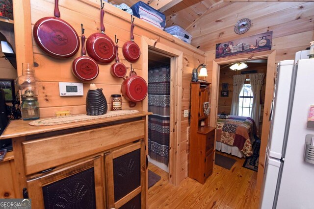 kitchen with wood ceiling, light wood-type flooring, vaulted ceiling, wood walls, and white fridge