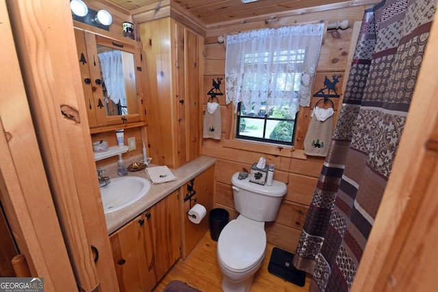 bathroom featuring hardwood / wood-style floors, wood walls, vanity, and toilet