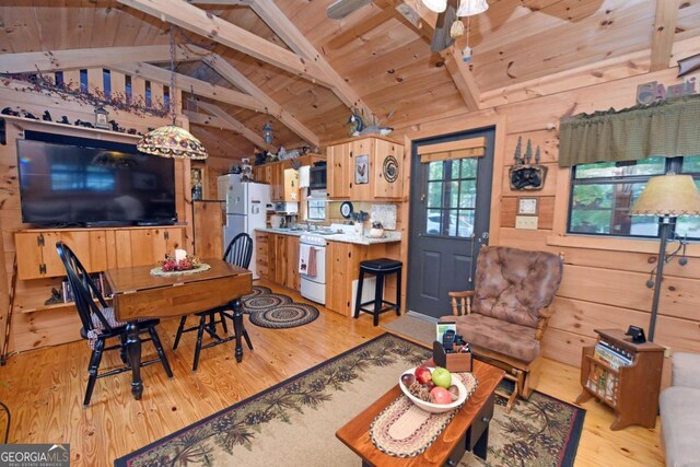 living room featuring vaulted ceiling with beams, wooden walls, and light wood-type flooring