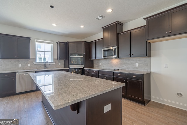 kitchen featuring backsplash, stainless steel appliances, light hardwood / wood-style flooring, and light stone counters