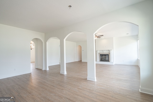 unfurnished living room featuring ceiling fan, light hardwood / wood-style flooring, and a high end fireplace