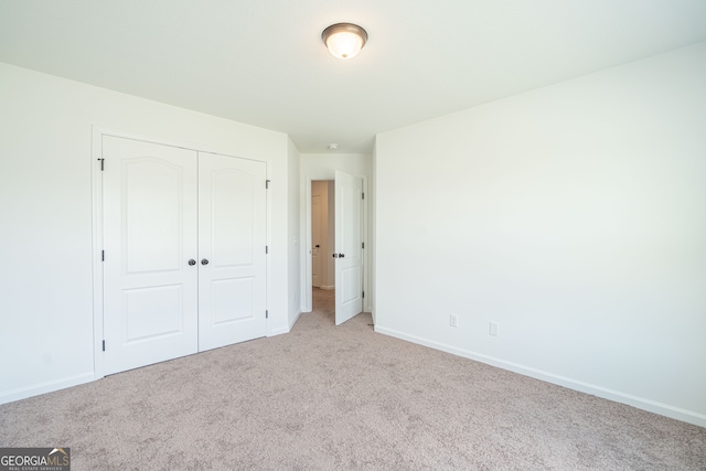 unfurnished bedroom with light carpet and a closet