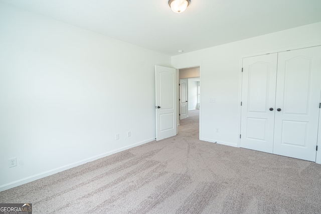 unfurnished bedroom with a closet and light colored carpet