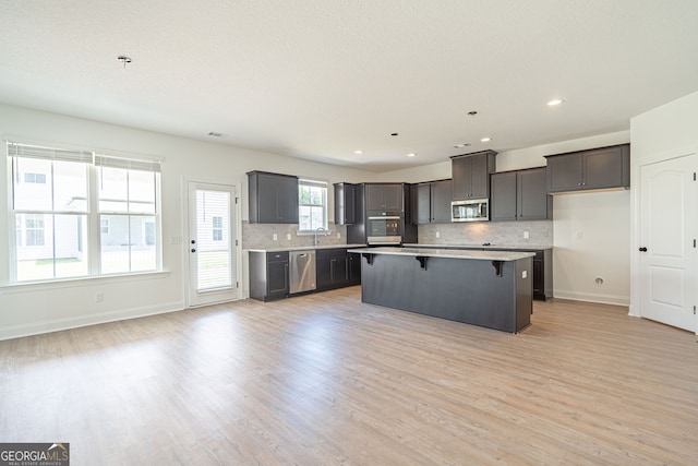 kitchen featuring tasteful backsplash, appliances with stainless steel finishes, a center island, and light hardwood / wood-style floors