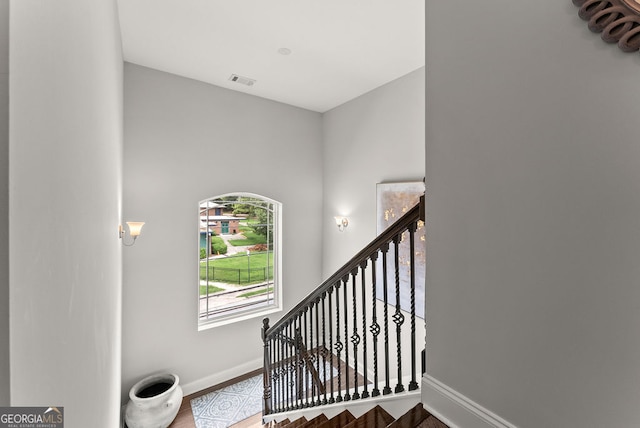 stairway with wood-type flooring and a high ceiling