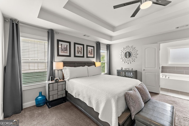 bedroom with ceiling fan, a raised ceiling, ensuite bathroom, and carpet floors