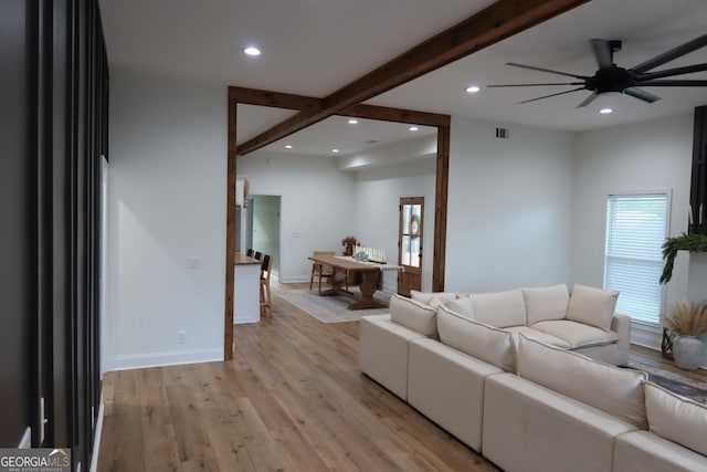 living room with beam ceiling, ceiling fan, and light wood-type flooring