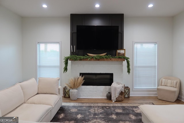 living room with hardwood / wood-style flooring and a brick fireplace