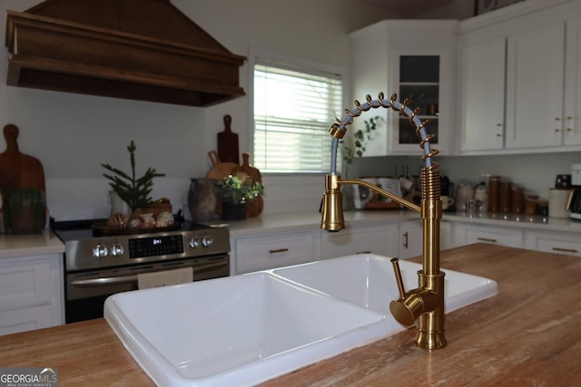 kitchen featuring white cabinets, electric range, and custom exhaust hood