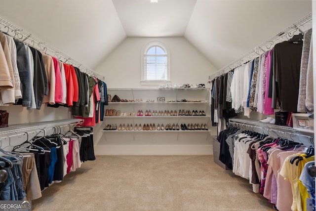 walk in closet with lofted ceiling and light carpet