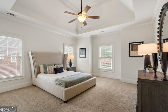 carpeted bedroom with ceiling fan, a raised ceiling, and multiple windows