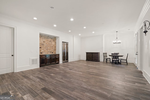 unfurnished living room featuring a notable chandelier, ornamental molding, and wood-type flooring