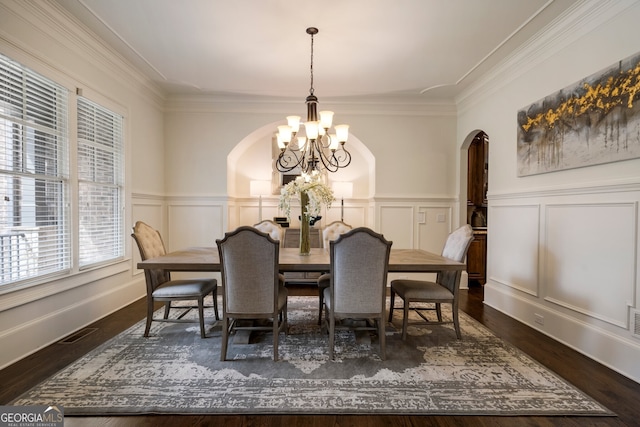 dining area featuring crown molding, dark wood-type flooring, and an inviting chandelier