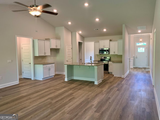 kitchen with appliances with stainless steel finishes, white cabinetry, a kitchen island with sink, and dark stone counters