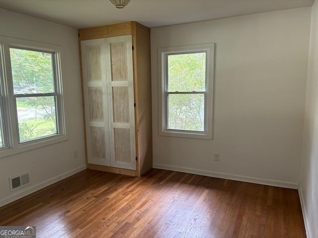 unfurnished bedroom with multiple windows and dark hardwood / wood-style floors