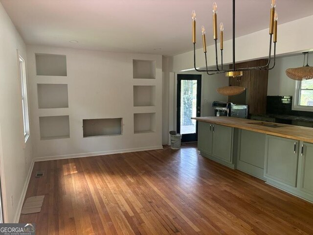 kitchen featuring dark wood-type flooring, wooden counters, built in shelves, and green cabinets