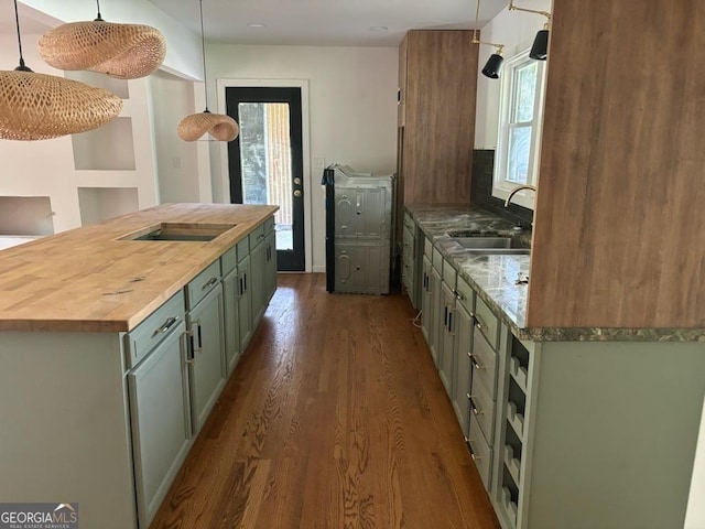 kitchen featuring wood counters, sink, hanging light fixtures, green cabinetry, and black electric cooktop