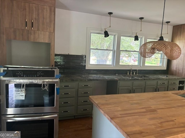 kitchen featuring pendant lighting, sink, wood counters, and stainless steel double oven