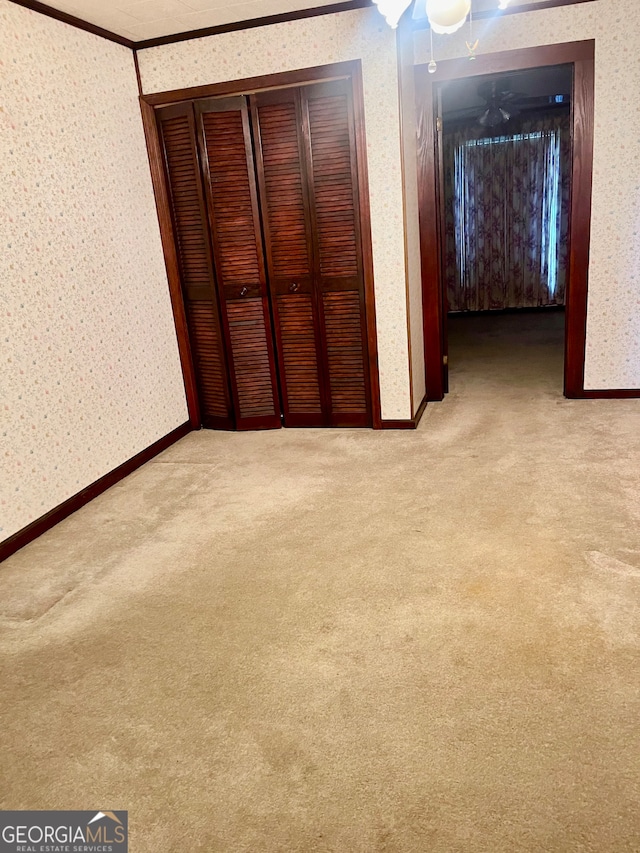 unfurnished bedroom featuring a closet, light colored carpet, and crown molding