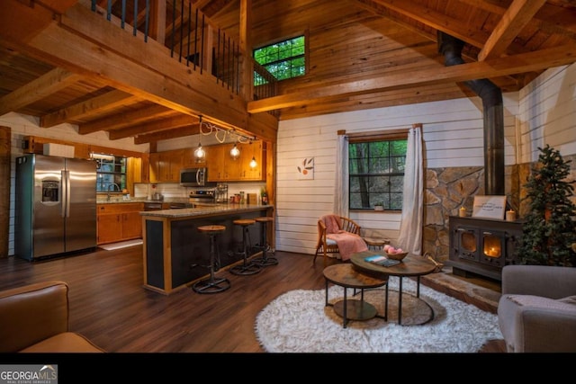 living room with beamed ceiling, a wood stove, dark wood-type flooring, and wood walls