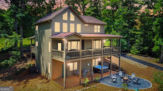 back house at dusk with central air condition unit and a patio area