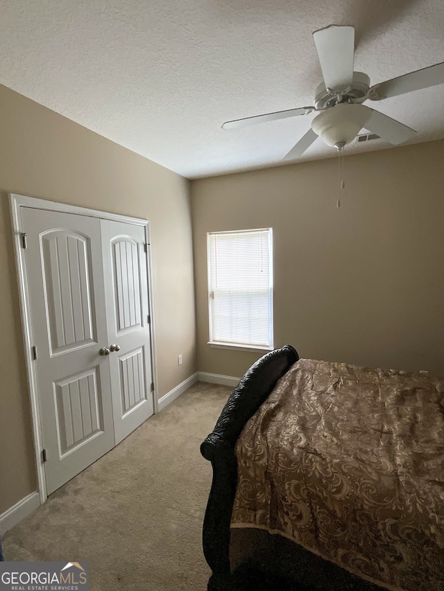 carpeted bedroom featuring a textured ceiling, a closet, and ceiling fan