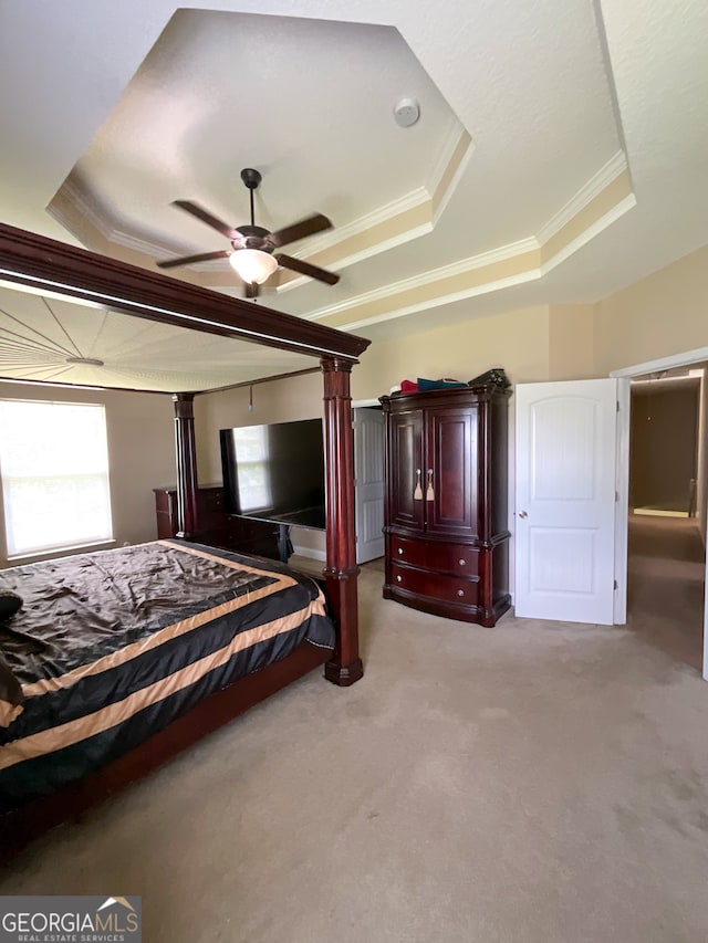 unfurnished bedroom featuring ceiling fan, a raised ceiling, crown molding, and light colored carpet