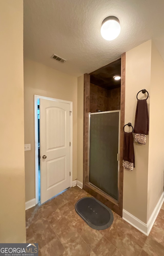 bathroom featuring tile patterned flooring, a textured ceiling, and walk in shower