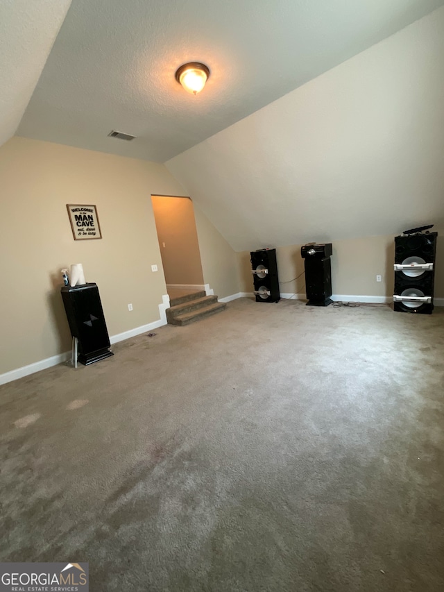 bonus room featuring a textured ceiling, carpet floors, and lofted ceiling