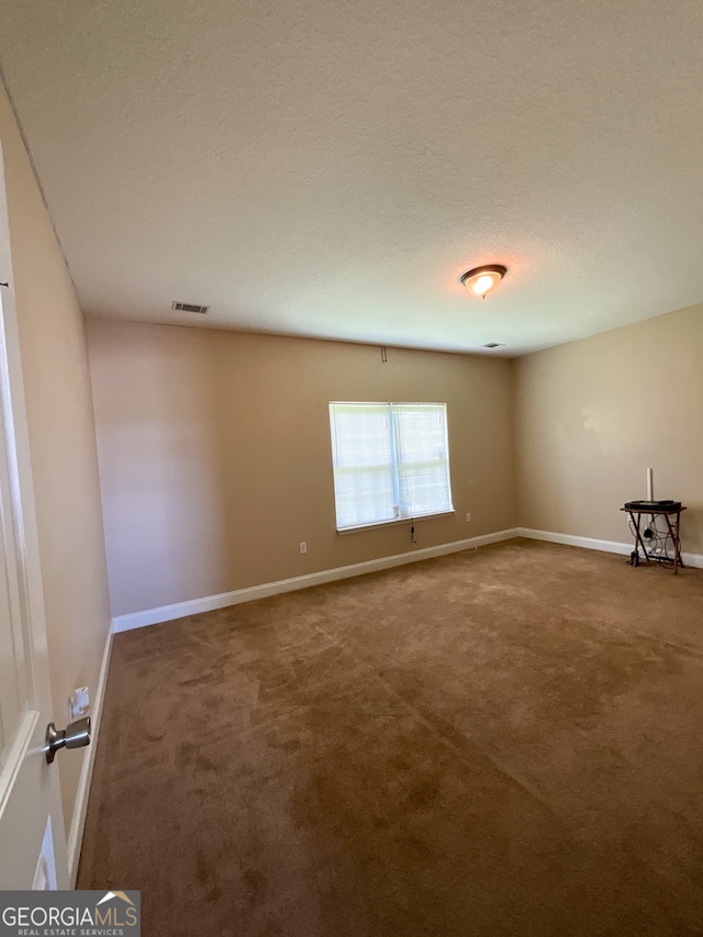 carpeted empty room with a textured ceiling