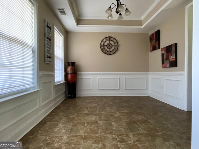 tiled empty room with a chandelier, crown molding, and a tray ceiling