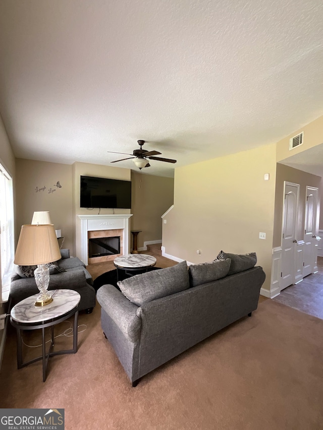 living room with a textured ceiling, carpet flooring, and ceiling fan